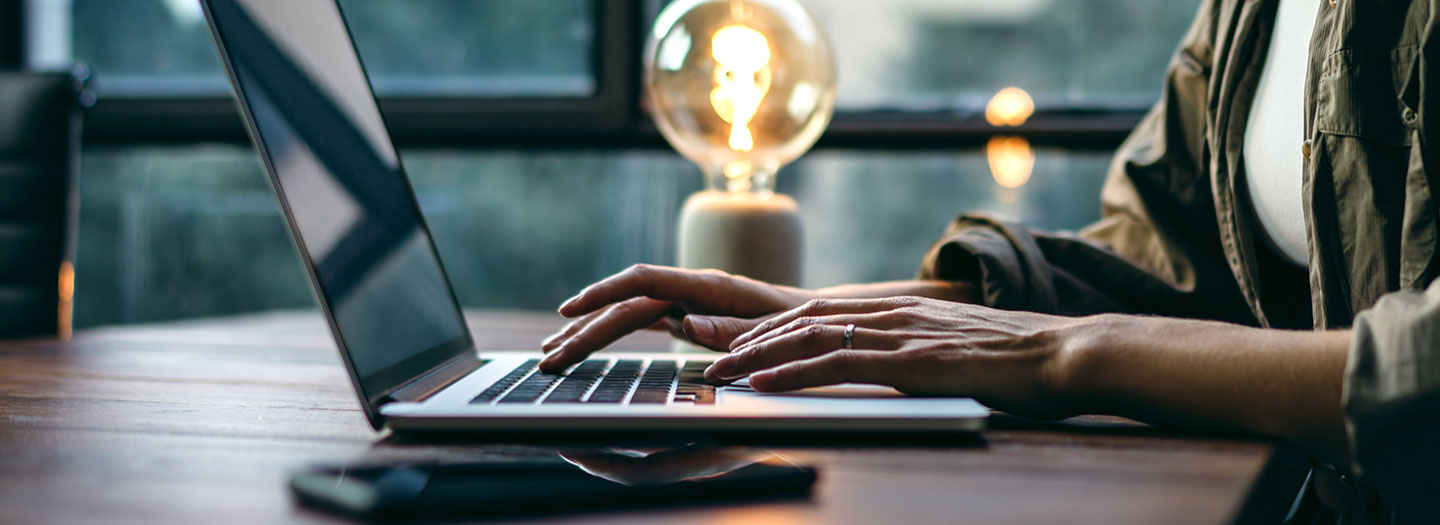 woman typing on laptop with inspiring lamp in background.